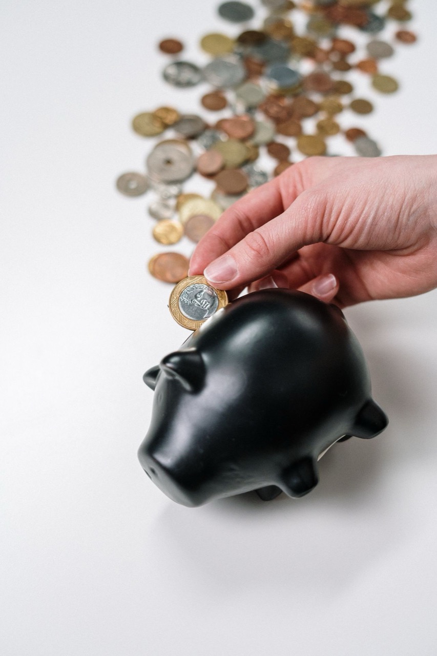 貯金箱にコインを入れる手／お金を貯める習慣のイメージ