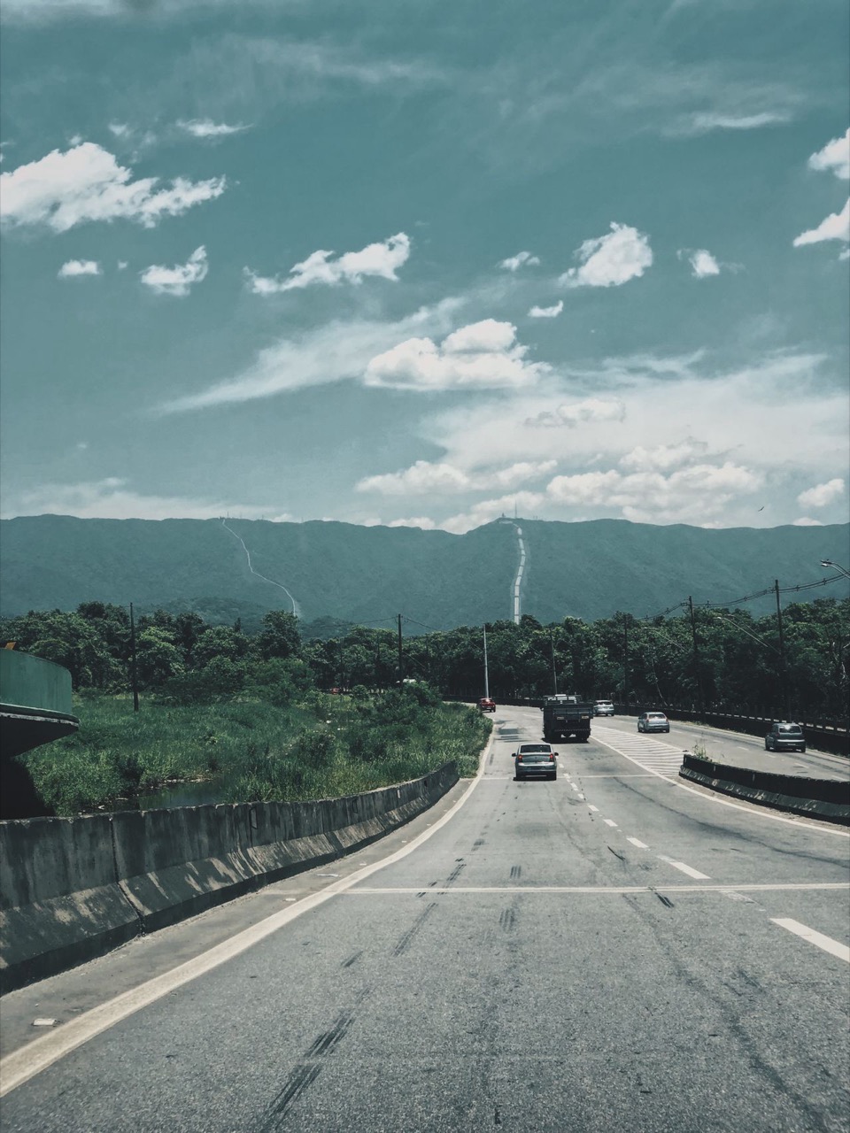 夏の青空の下、山に向かって走る車と高速道路／1泊のドライブ旅行のイメージ