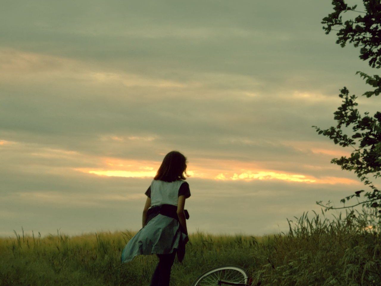 夕暮れの空の下、自転車と一緒に立ち止まる女の子のイメージ